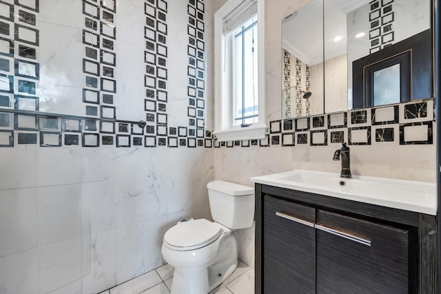 bathroom with tile walls, toilet, vanity, and tile patterned floors
