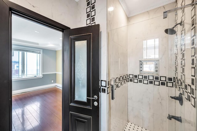 bathroom with ornamental molding, a stall shower, baseboards, and wood finished floors