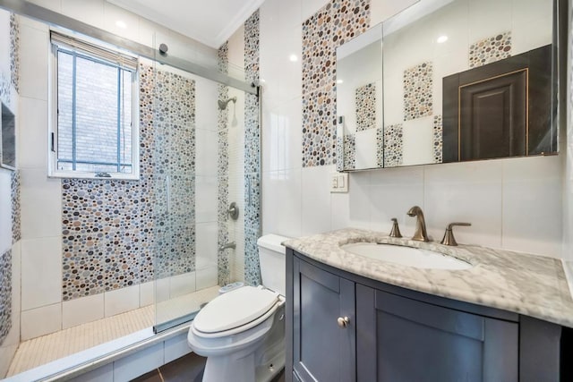 full bathroom with toilet, a stall shower, vanity, and tile walls