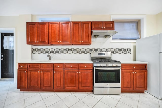 kitchen with stainless steel gas stove, freestanding refrigerator, a sink, and light countertops