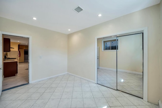 unfurnished bedroom featuring recessed lighting, light tile patterned flooring, baseboards, and a closet