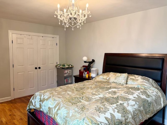 bedroom featuring a closet, a chandelier, wood finished floors, and baseboards