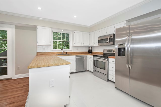 3 Kitchel Rd, Mount Kisco, NY 10549 - kitchen featuring appliances with stainless steel finishes, crown molding, white cabinetry, tasteful backsplash, and butcher block counters