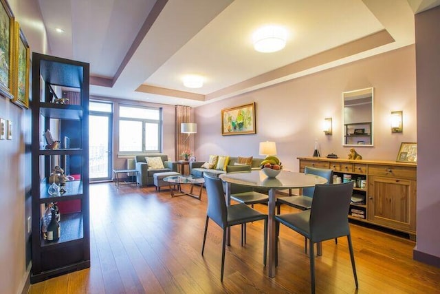 dining area featuring a raised ceiling and wood finished floors