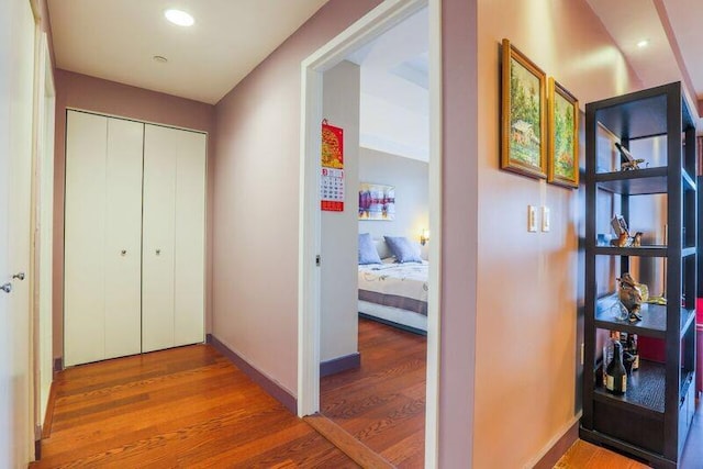 corridor with wood finished floors, baseboards, and recessed lighting