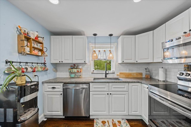 kitchen featuring appliances with stainless steel finishes, a sink, dark wood-style floors, and white cabinetry
