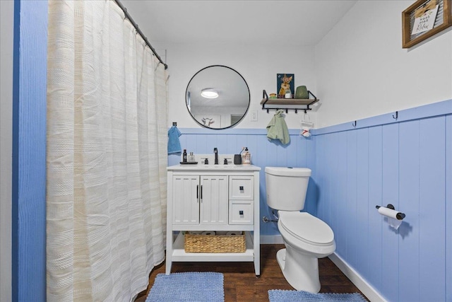 full bathroom featuring wood finished floors, toilet, a wainscoted wall, vanity, and a shower with curtain