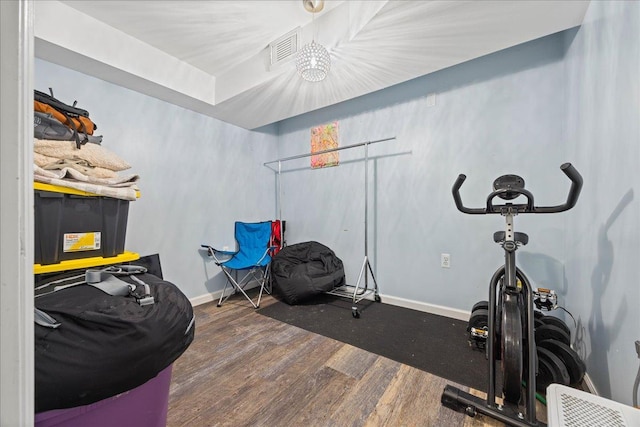 workout area featuring wood finished floors, baseboards, and a chandelier