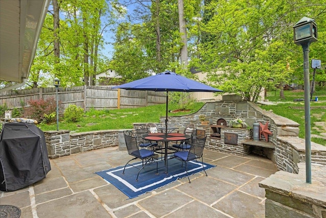 view of patio / terrace featuring an outdoor stone fireplace, outdoor dining area, a grill, and a fenced backyard