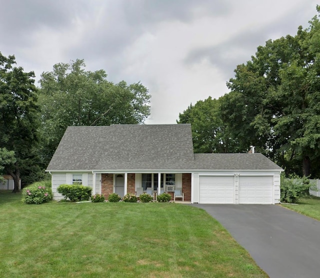 cape cod house with a garage, asphalt driveway, and a front lawn