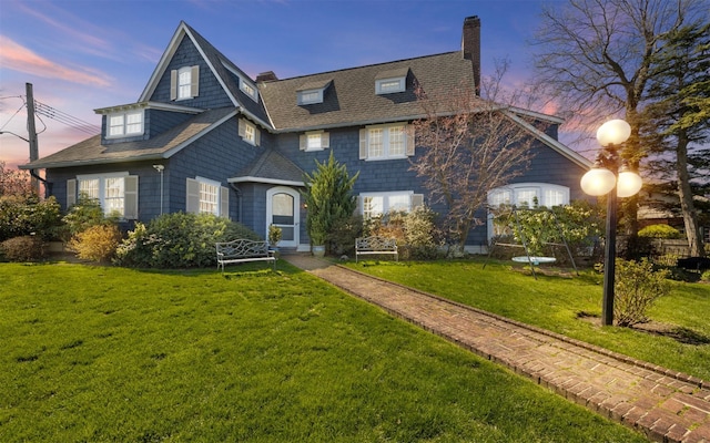 shingle-style home with a front lawn, a chimney, and roof with shingles