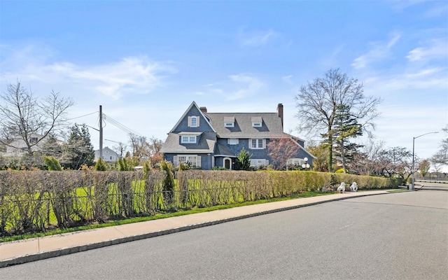 shingle-style home featuring fence and a chimney