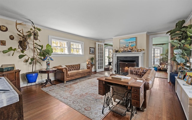 living area with ornamental molding, wood finished floors, and a lit fireplace