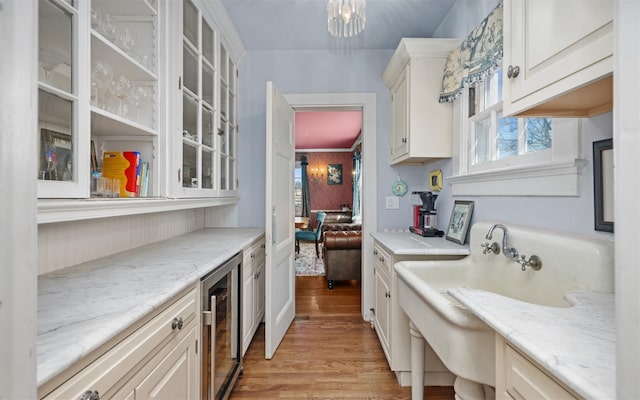 kitchen featuring wine cooler, light wood finished floors, glass insert cabinets, and plenty of natural light