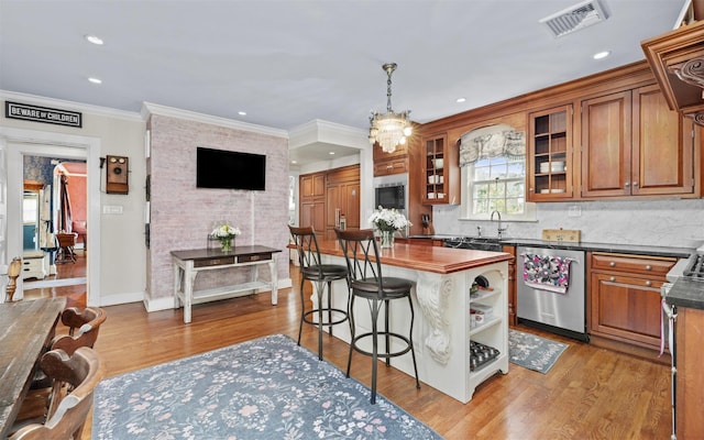 kitchen with stainless steel dishwasher, brown cabinetry, a breakfast bar, a sink, and tasteful backsplash
