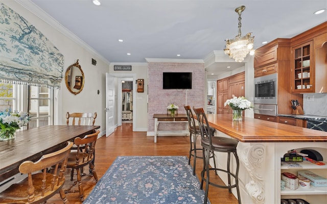 kitchen with a warming drawer, stainless steel microwave, brown cabinets, recessed lighting, and a chandelier