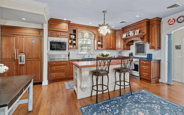 kitchen with built in appliances, brown cabinets, a sink, a warming drawer, and recessed lighting