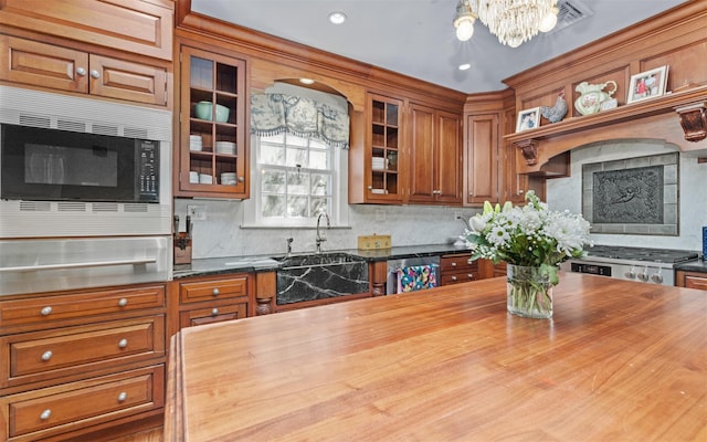 kitchen with wooden counters, stainless steel appliances, a warming drawer, a chandelier, and brown cabinetry