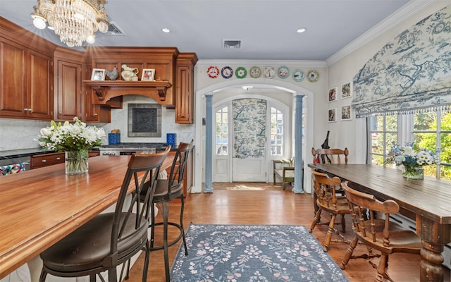 kitchen with arched walkways, plenty of natural light, brown cabinets, and crown molding