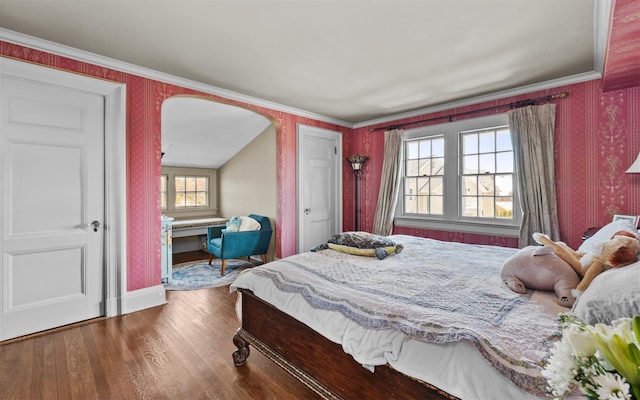 bedroom with wallpapered walls, wood finished floors, multiple windows, baseboards, and arched walkways