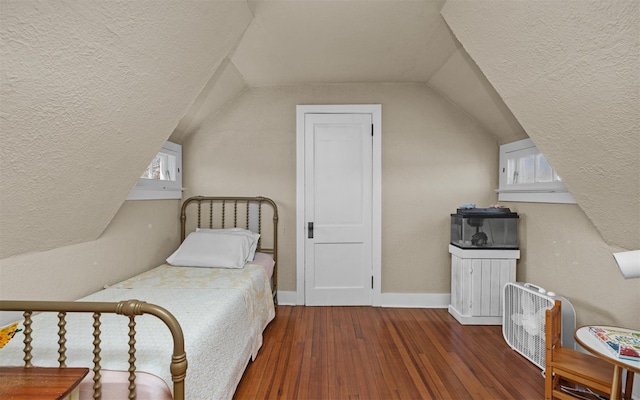 bedroom featuring a textured ceiling, wood-type flooring, lofted ceiling, baseboards, and multiple windows