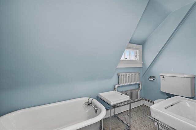 full bath featuring a soaking tub, toilet, and baseboards