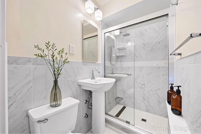bathroom featuring tile walls, a shower stall, toilet, and wainscoting
