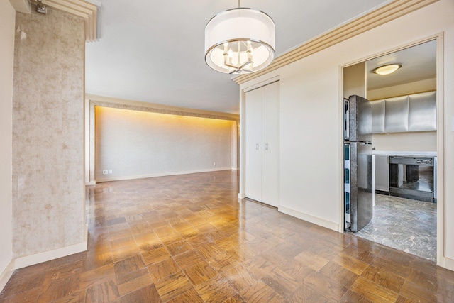 unfurnished room featuring a chandelier and baseboards