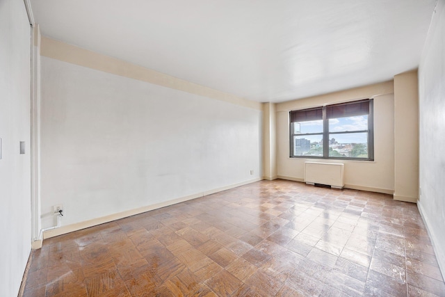 unfurnished room featuring radiator and baseboards