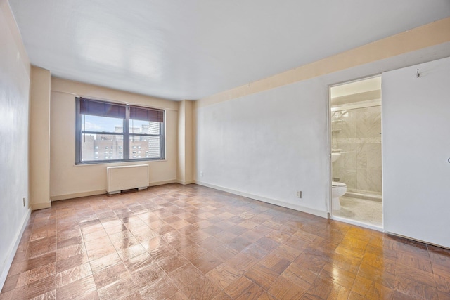empty room featuring radiator and baseboards