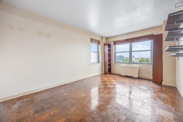 unfurnished room with radiator heating unit and baseboards