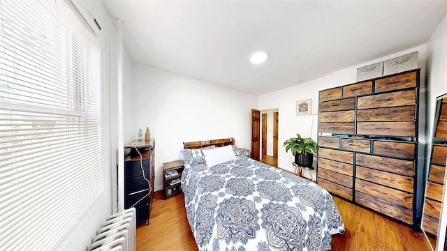 bedroom with radiator heating unit and wood finished floors