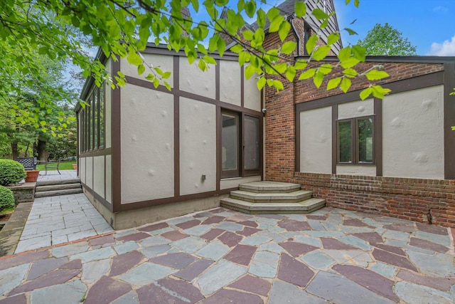 1 Wensley Dr, Great Neck, NY 11021 - back of property featuring brick siding, stucco siding, and a patio