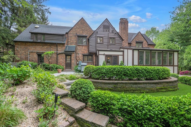 1 Wensley Dr, Great Neck, NY 11021 - view of front of house with brick siding, a chimney, and a sunroom