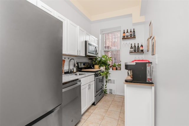 kitchen featuring stainless steel appliances, a sink, white cabinets, and light tile patterned floors