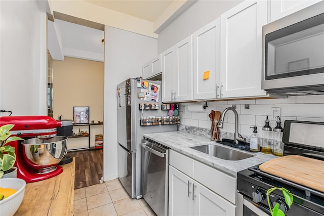kitchen featuring stainless steel appliances, a sink, white cabinetry, and backsplash