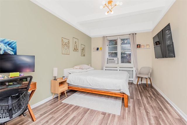 bedroom featuring radiator heating unit, light wood-style floors, baseboards, and a chandelier