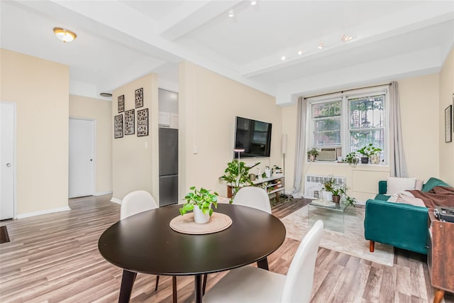 dining room featuring light wood-style floors, beamed ceiling, baseboards, and cooling unit
