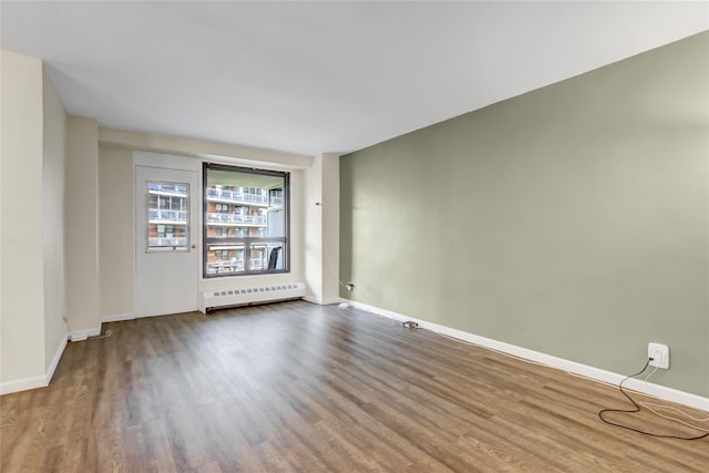 61-35 98th St Unit 4J, Rego Park, NY 11374 - empty room with a baseboard heating unit, wood finished floors, baseboards, and radiator heating unit