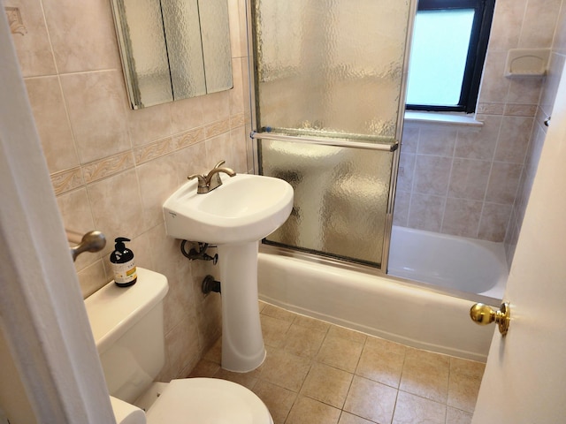 61-35 98th St Unit 4J, Rego Park, NY 11374 - bathroom featuring toilet, tile patterned floors, tile walls, and bath / shower combo with glass door