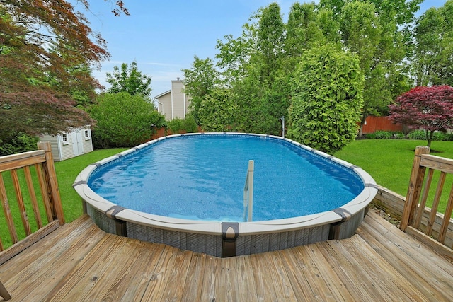 swimming pool featuring a deck, a yard, a storage shed, and an outbuilding