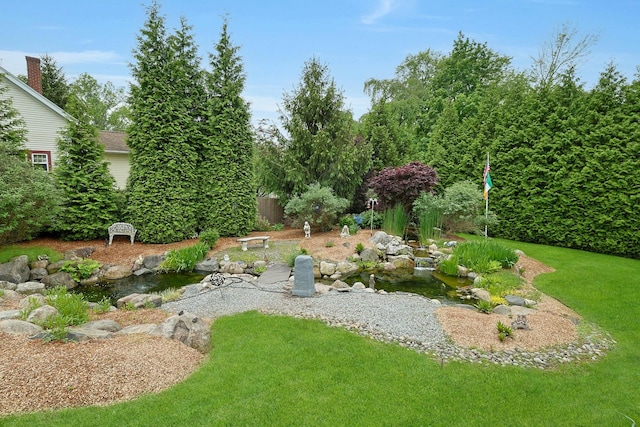 view of grassy yard featuring a small pond