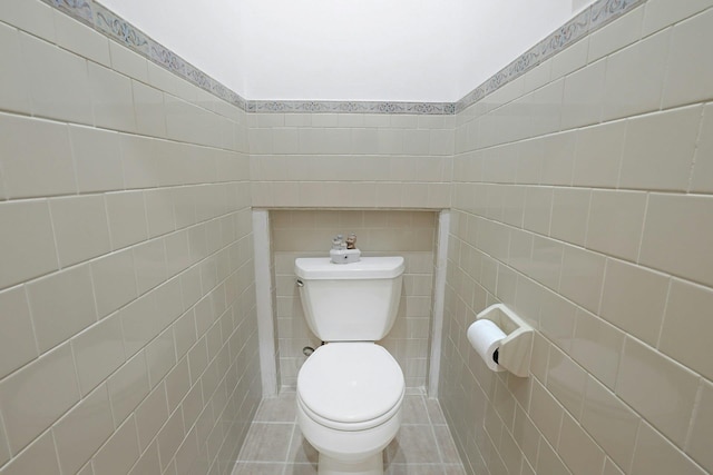 bathroom with toilet, tile walls, and tile patterned flooring