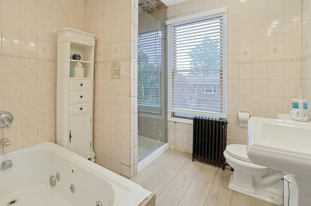 full bath featuring tile walls, radiator, healthy amount of natural light, a shower stall, and a jetted tub