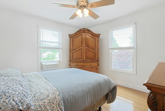 bedroom featuring light wood-style floors, ceiling fan, baseboards, and cooling unit
