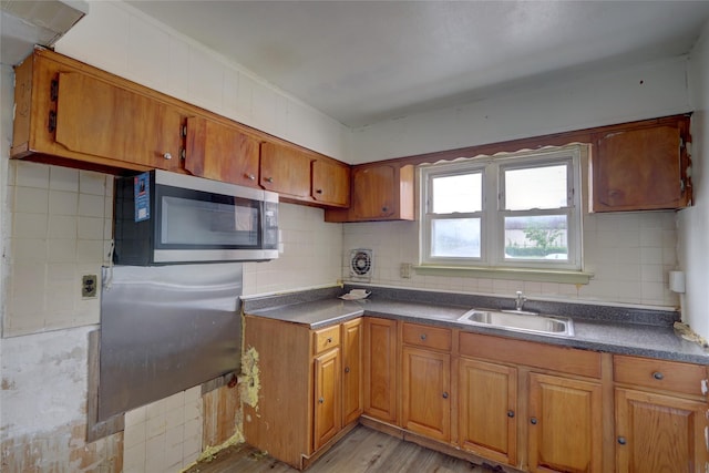122-52 Springfield Blvd, Springfield Gardens, NY 11413 - kitchen with stainless steel microwave, a sink, brown cabinetry, decorative backsplash, and light wood-style flooring