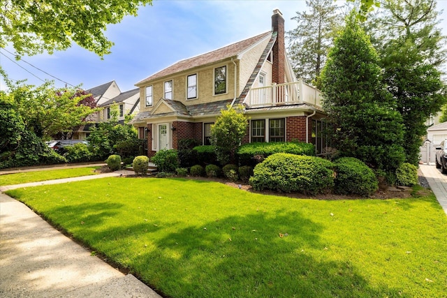 265 Brower Ave, Rockville Centre, NY 11570 - view of front of house with brick siding, a front lawn, a balcony, and a chimney