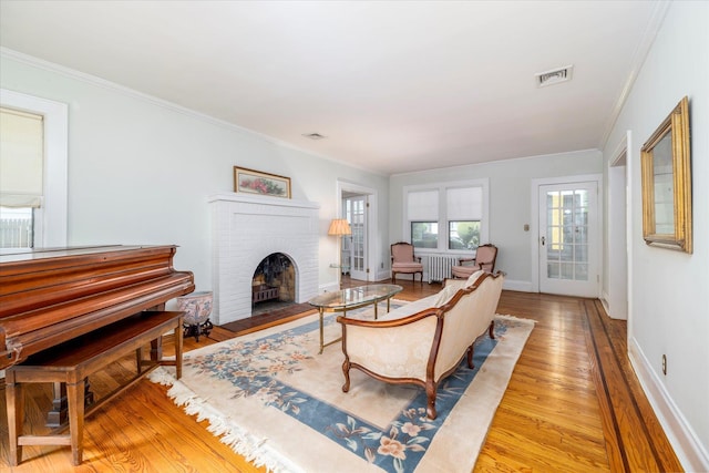265 Brower Ave, Rockville Centre, NY 11570 - living room featuring wood finished floors, ornamental molding, a brick fireplace, and radiator