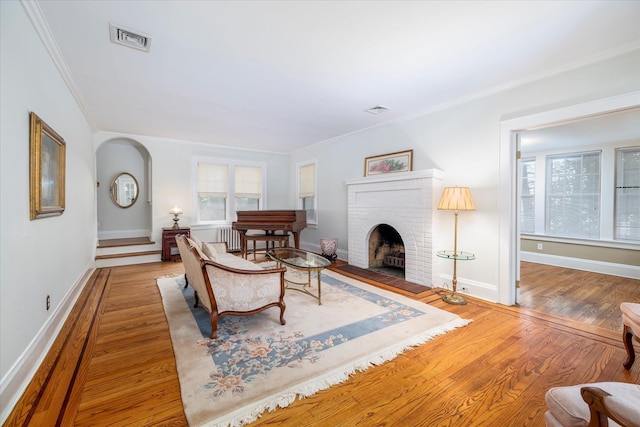 265 Brower Ave, Rockville Centre, NY 11570 - living area with crown molding, plenty of natural light, wood finished floors, a brick fireplace, and arched walkways