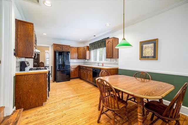 265 Brower Ave, Rockville Centre, NY 11570 - kitchen featuring black appliances, ornamental molding, light countertops, light wood-style floors, and brown cabinets